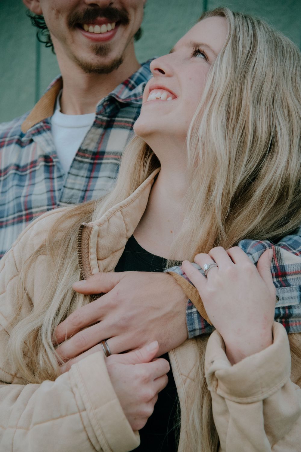 An intimate close-up of a couple embracing against a teal background.