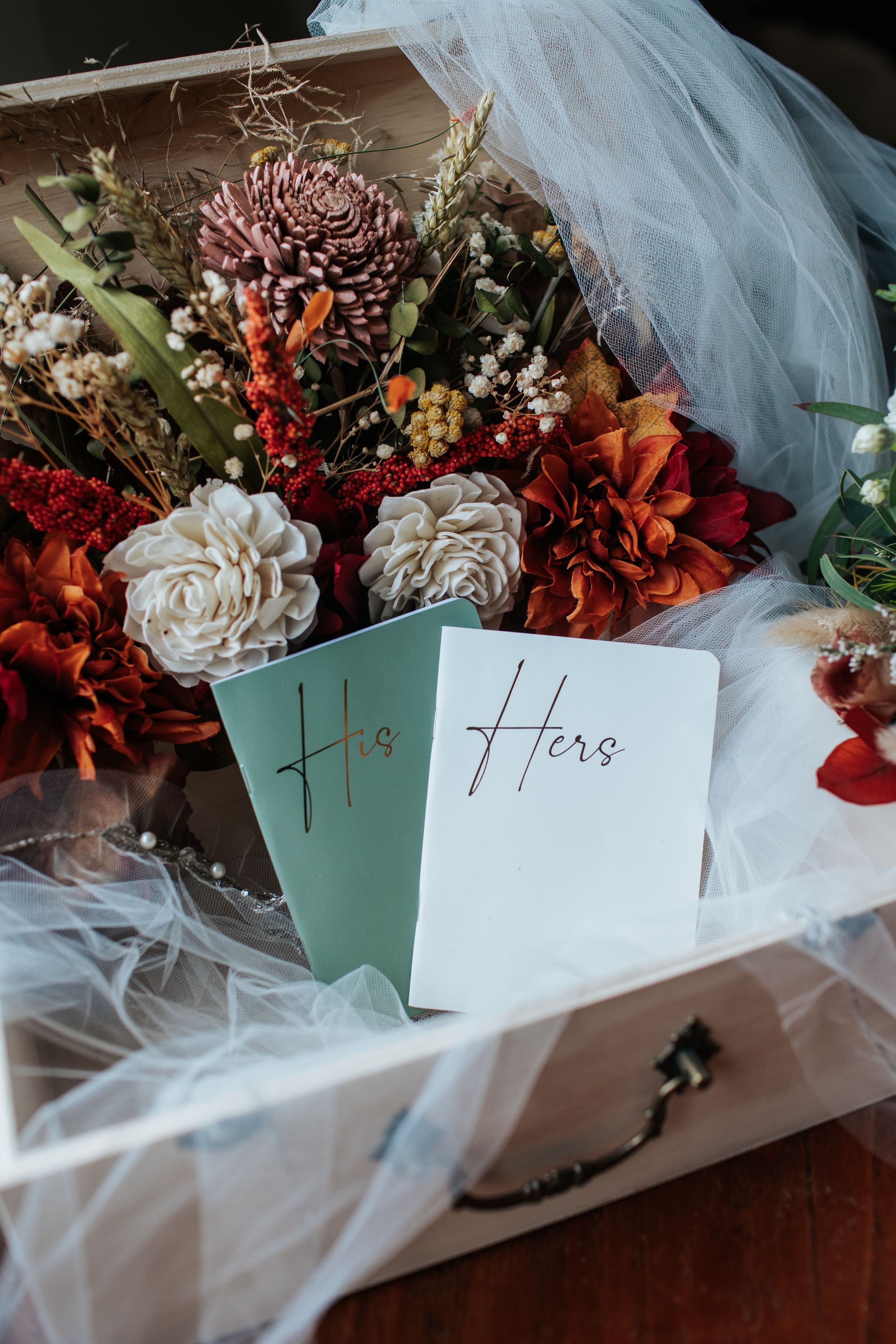 Wedding bouquets wrapped in tulle with mint green name cards arranged in a row on dark wooden surface.