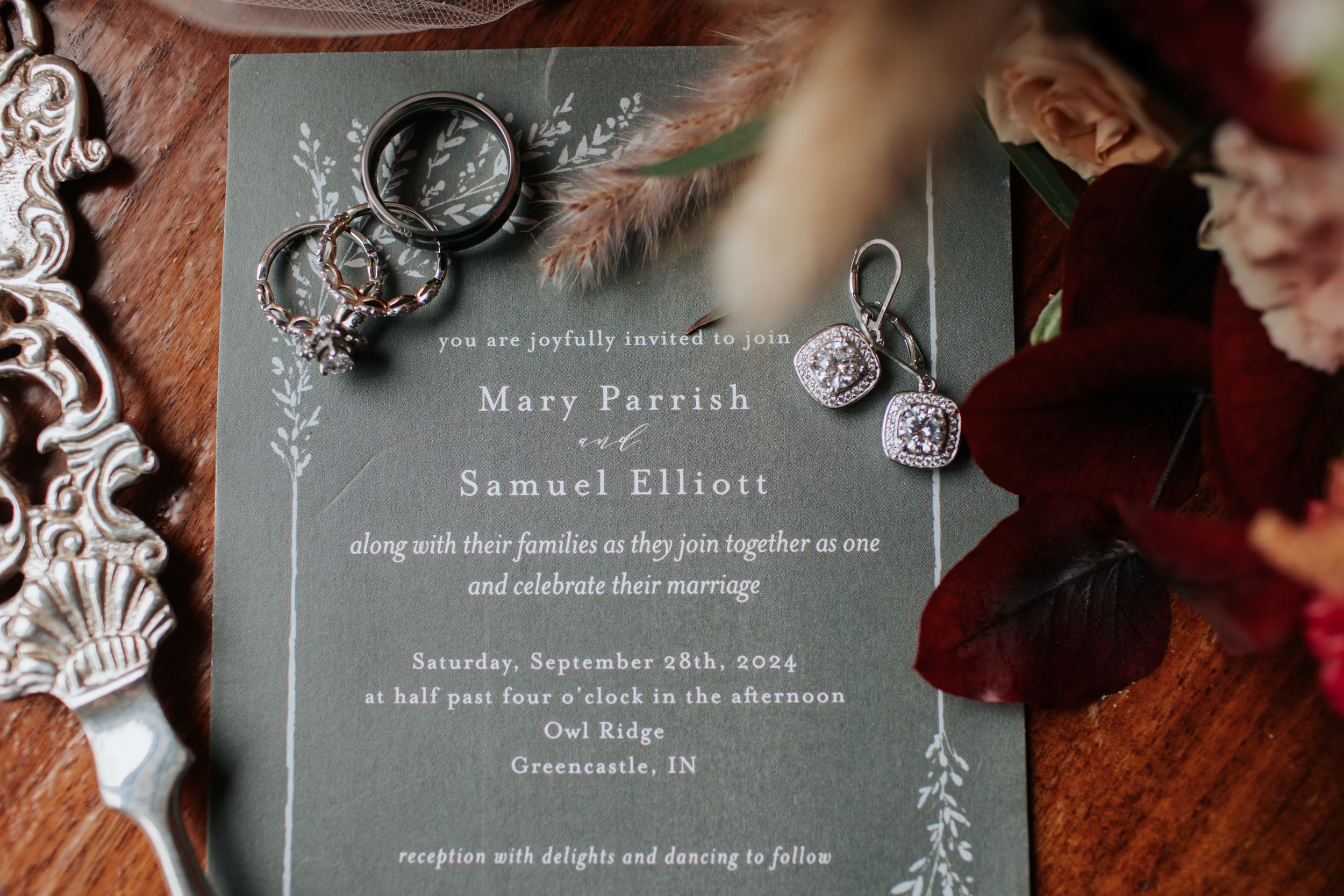 Elegant wedding invitation suite with sage green and white floral design displayed with decorative elements.
