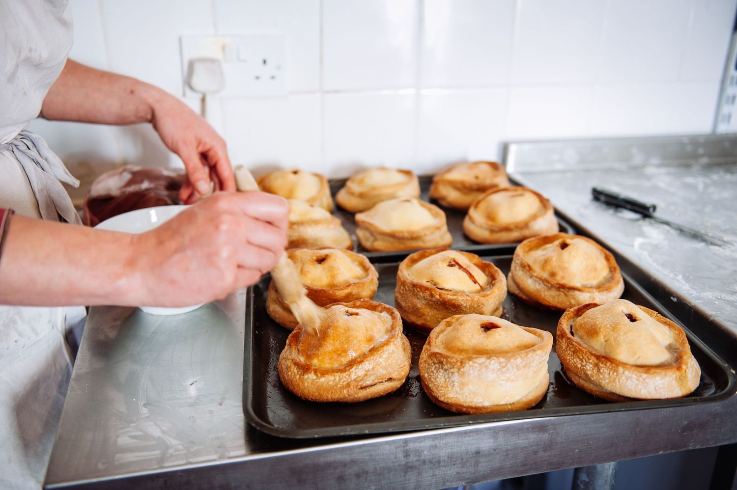Golden brown Yorkshire puddings cooling on a metal baking tray.