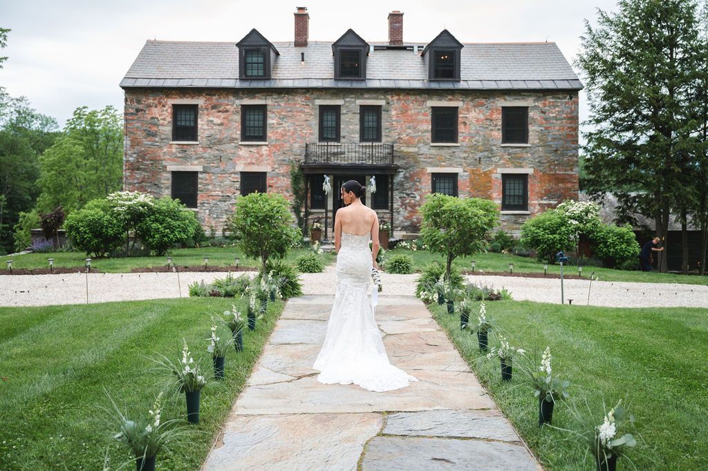 Bride in long elegant white dress in front of historic Stone House at Ruins at Sassafras wedding venue New Lebanon NY in Hudson Valley
