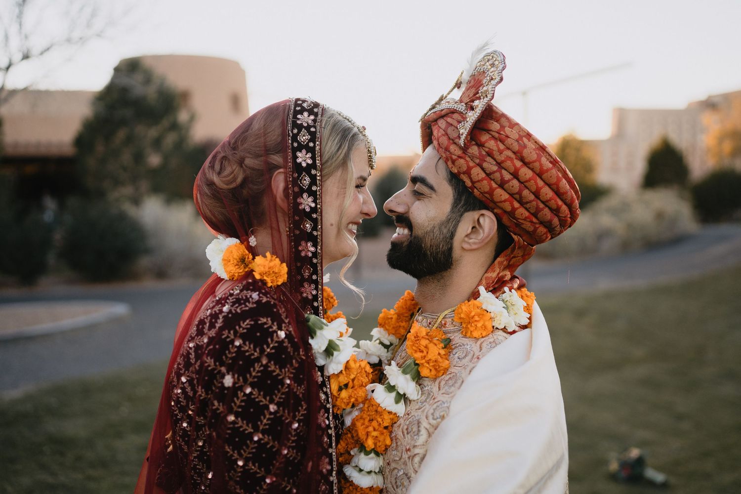 Indian bride and groom in traditional wedding attire sharing intimate moment with marigold garlands. at Sandia Resort and Casino