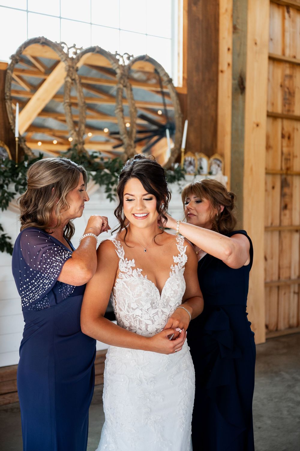 Wedding dress preparation in rustic barn venue with decorative backdrop.