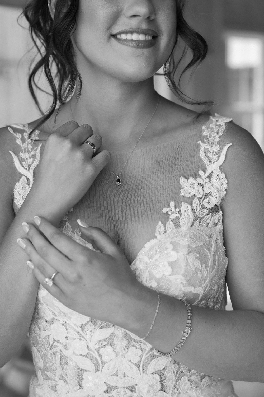Close up of delicate lace details on wedding dress with jewelry accents.