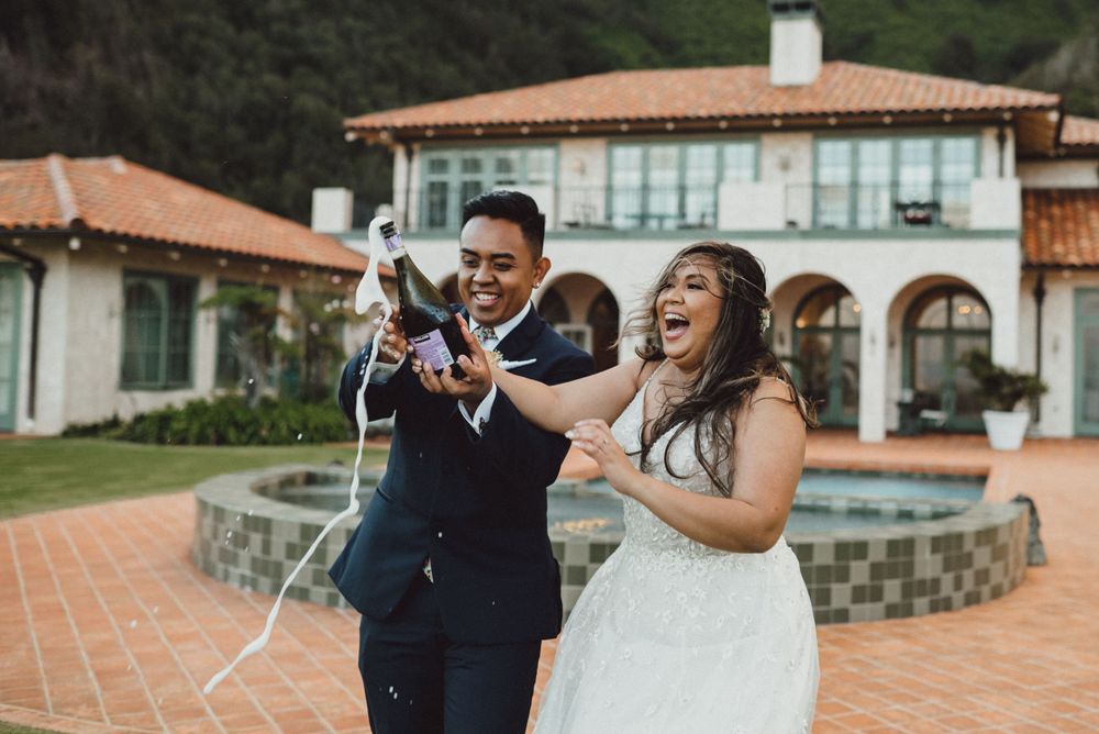 A couple laughs together during their wedding photoshoot at a Spanish-style venue.