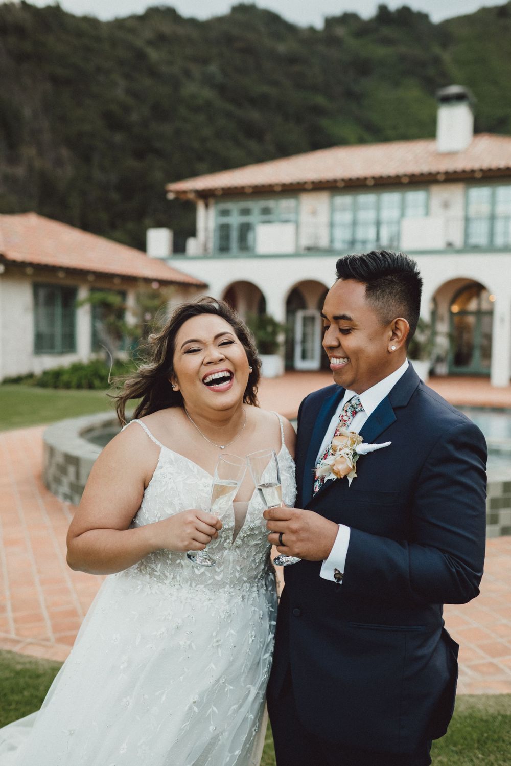 A couple shares candid laughter during their outdoor wedding photoshoot.