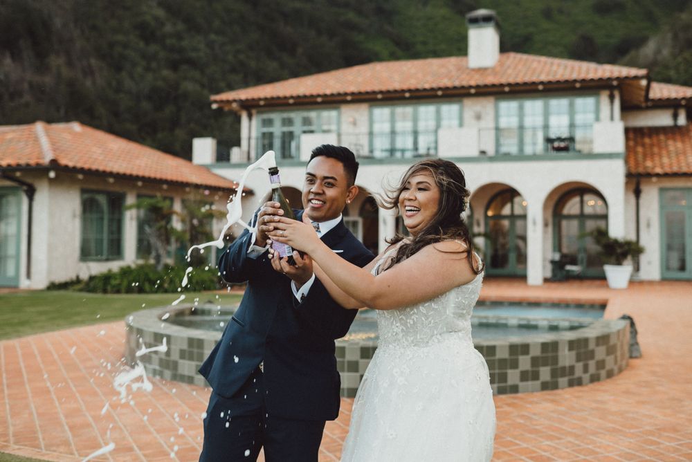 A couple celebrates their wedding day with laughter at a Mediterranean-style venue.