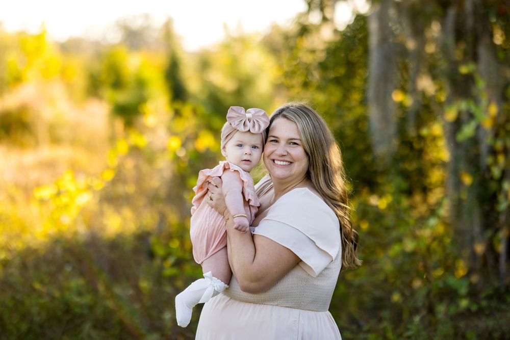 Parent and child share joyful moments together in a golden sunlit outdoor setting during a photo session.