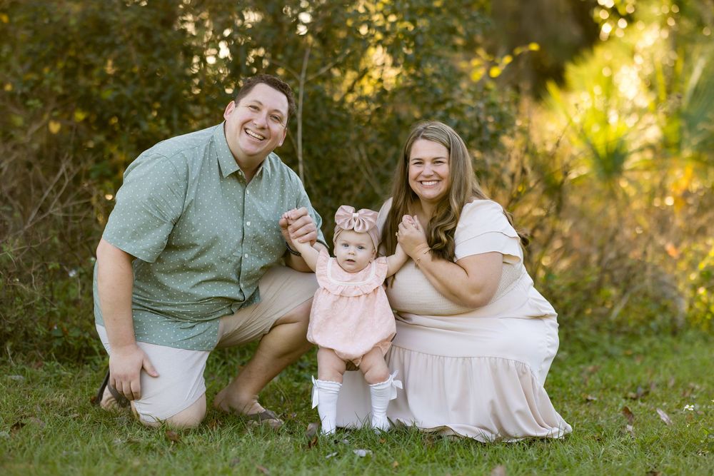 Family sitting together on grass during golden hour sunset in a park setting.