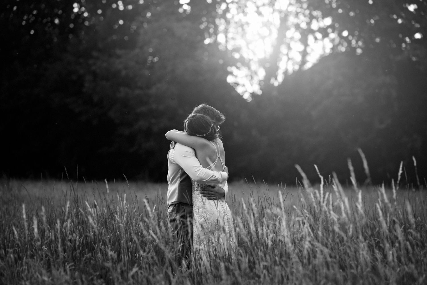 A panoramic black and white photo series showing a person walking through tall grass in a sunlit meadow.