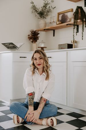 Relaxed indoor photoshoot on black and white checkered floor with plants in background.