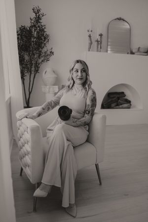 Artistic black and white photos of someone posing elegantly on a white armchair in a minimalist setting.