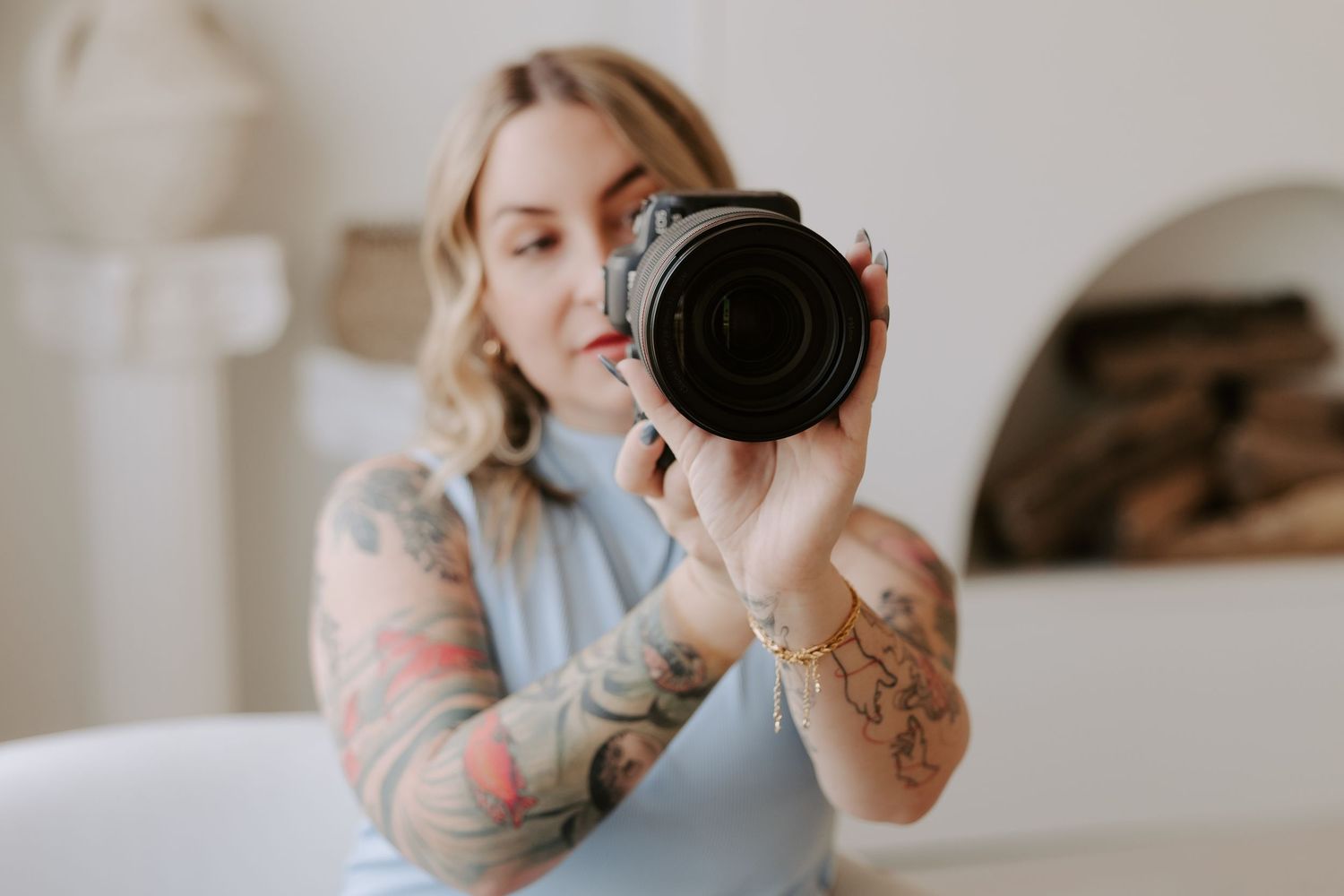 Creative self-portrait session with camera and visible tattoo artwork.