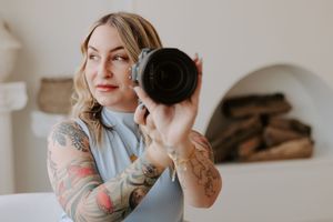 Artistic mirror self-portrait showing camera and tattoo details.