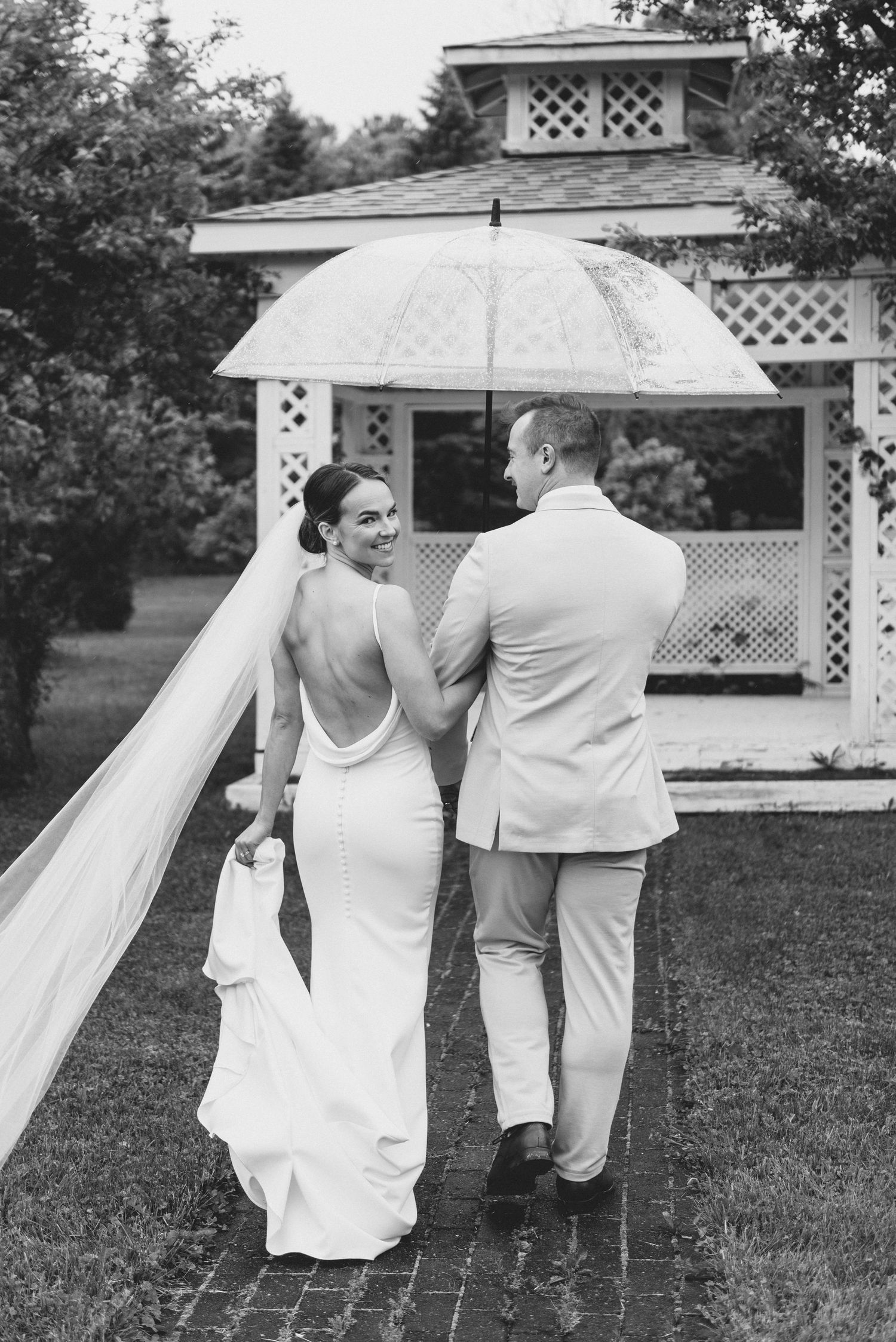 Black and white photo sequence of newlyweds running playfully through a garden with white gazebos.
