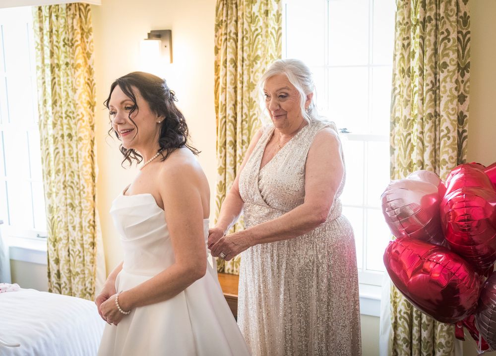 A series of getting ready moments showing a white wedding dress being put on in a room with floral curtains.