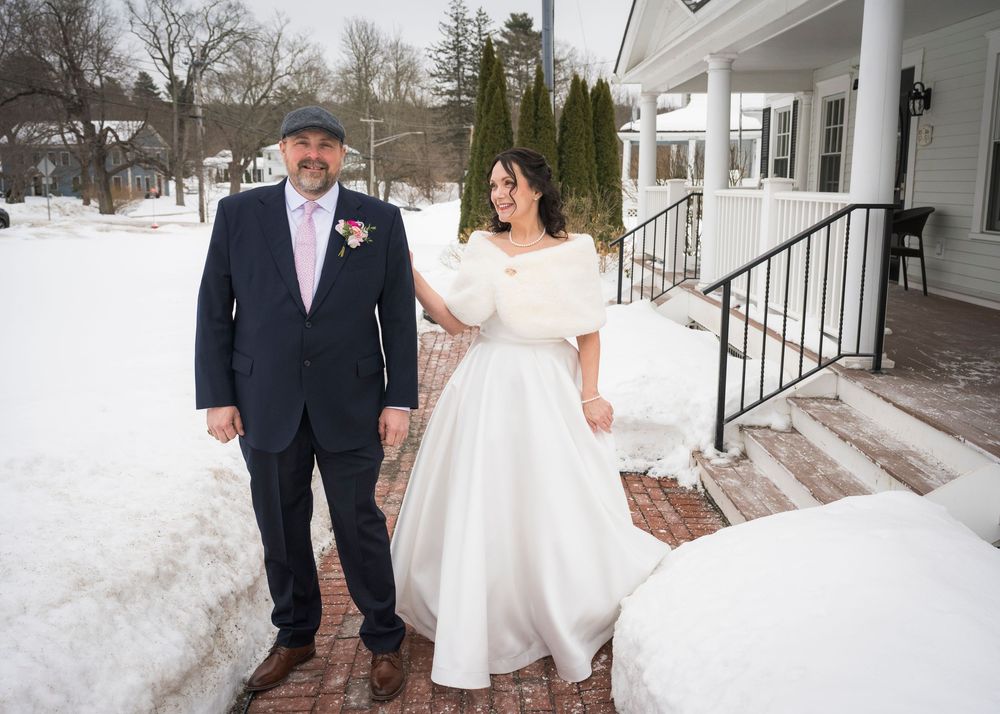 Winter wedding photo shoot with snow covered grounds and white colonial style building in background.