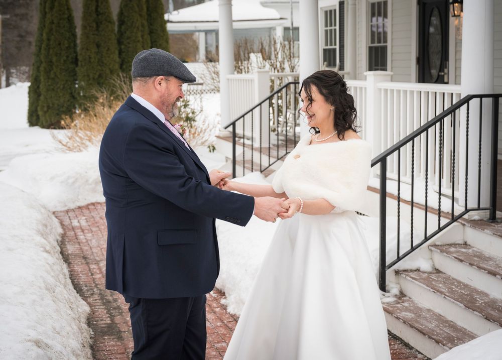 Winter wedding first look photos captured on snowy steps with white columns.