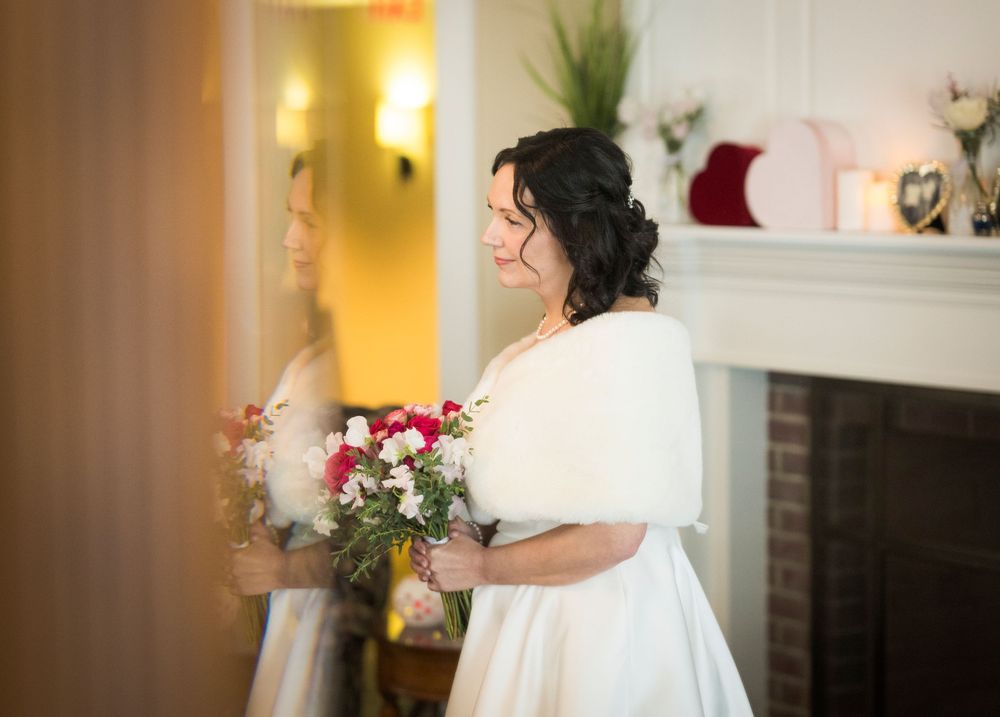 Romantic winter wedding scene with couple dancing in a warmly lit indoor venue with festive holiday decor.