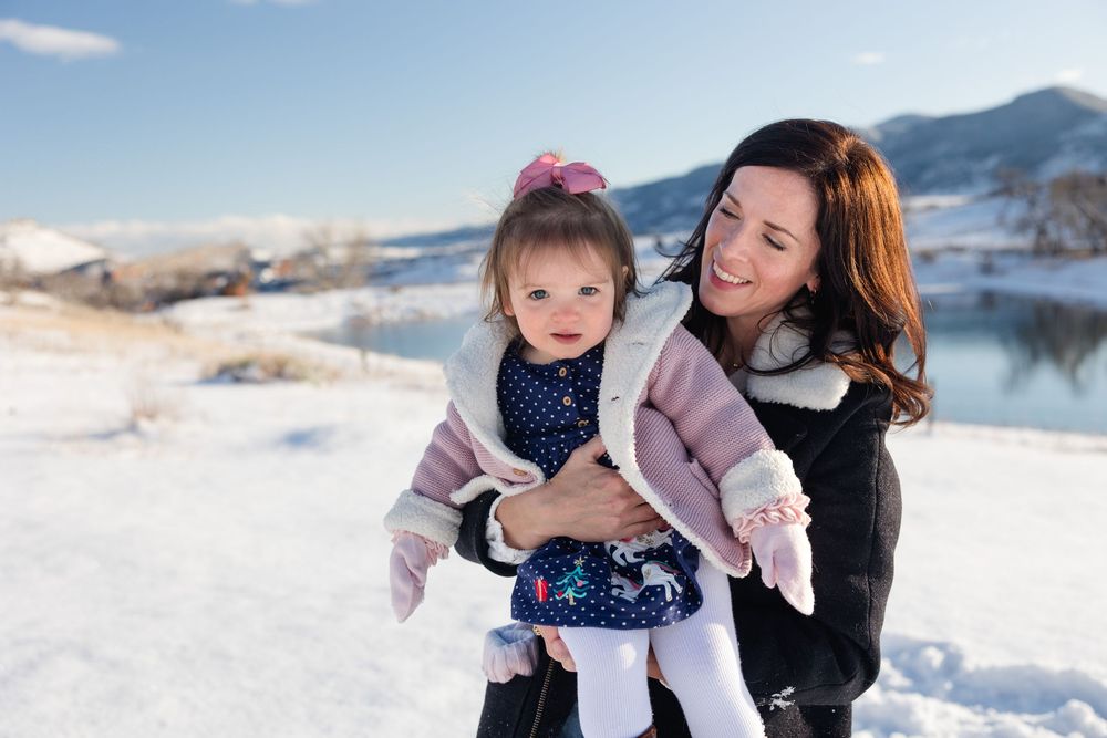A series of candid winter moments captured in the snow with a child wearing a pink jacket and navy polka dot dress.