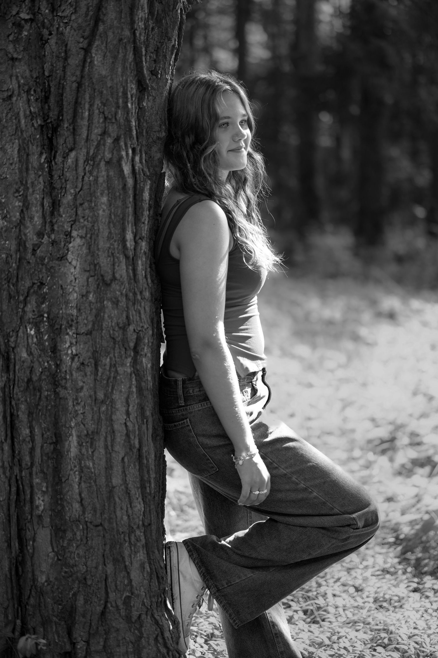 Black and white artistic photo series showing someone leaning against a tree trunk in a forest setting.
