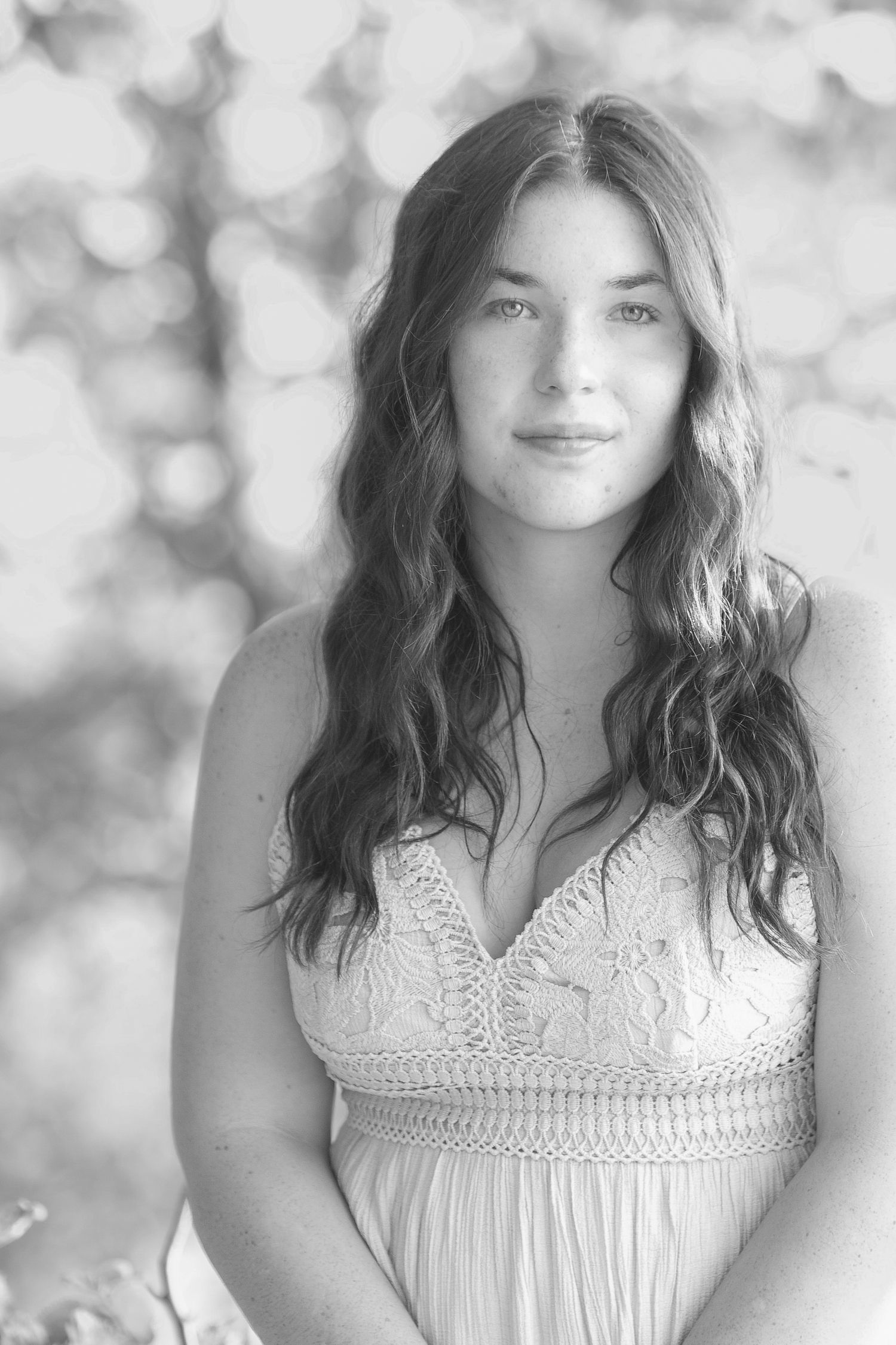 A series of soft black and white portraits showing someone in a white lace dress against a dreamy bokeh background.