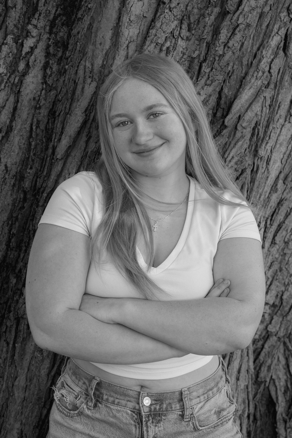 A series of black and white portraits showing someone in a white top and denim against a textured tree bark background.