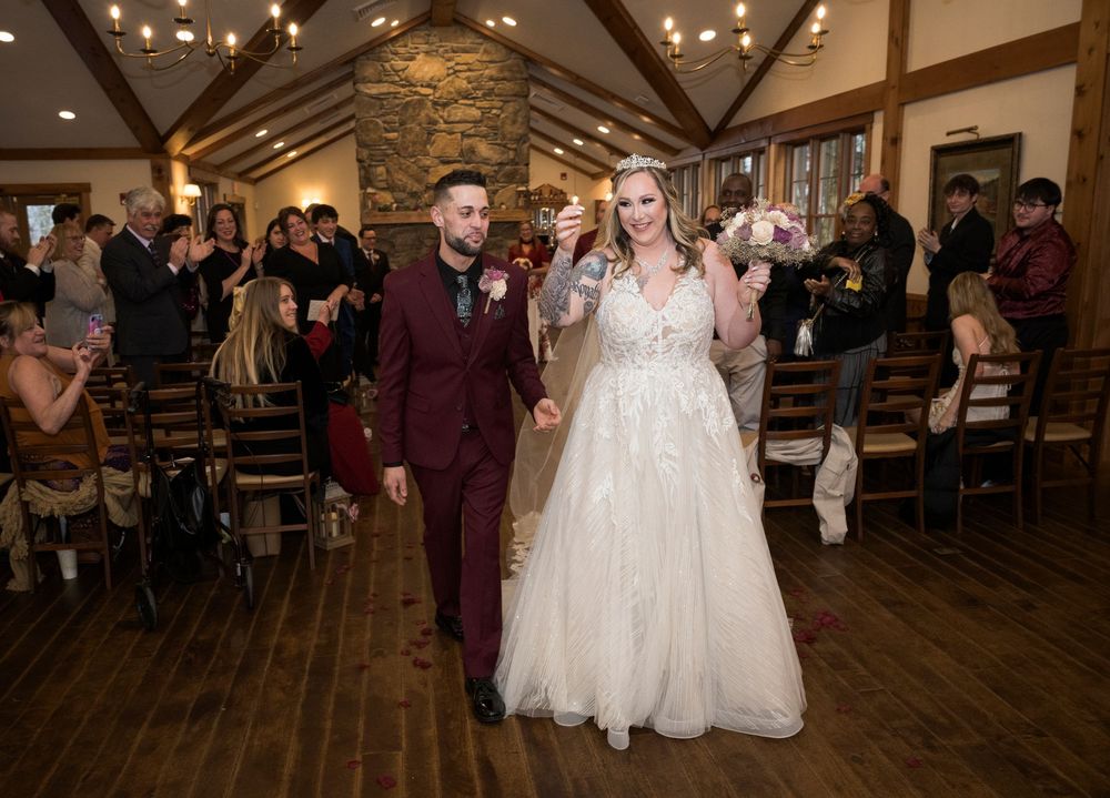 Newlywed couple walks down the aisle hand-in-hand after wedding ceremony in a rustic wood and stone venue.