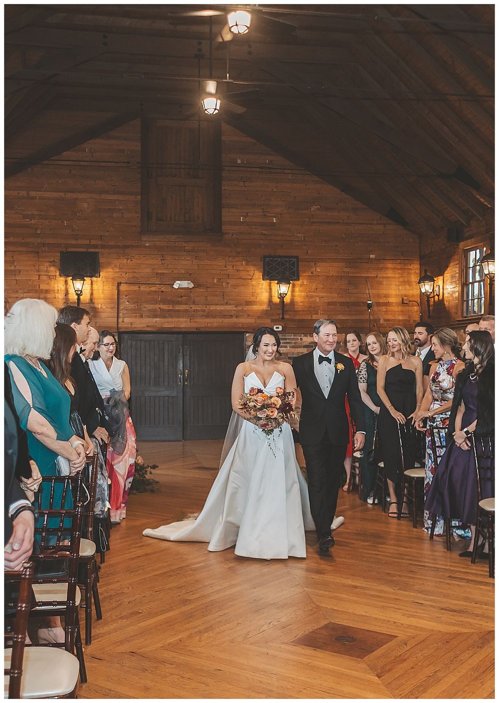 A wedding ceremony in a rustic wooden barn venue with warm lighting and hardwood floors.