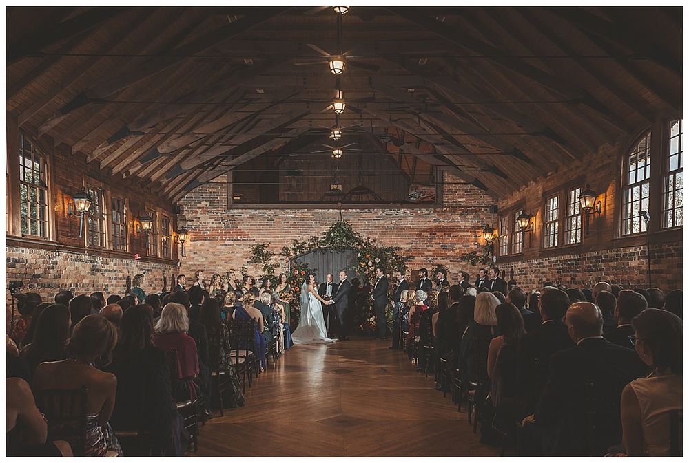 Large rustic indoor venue with exposed wooden beams and warm lighting creating an atmospheric event space.