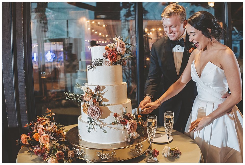 Wedding cake display with champagne glasses and autumn floral decorations at an elegant reception.