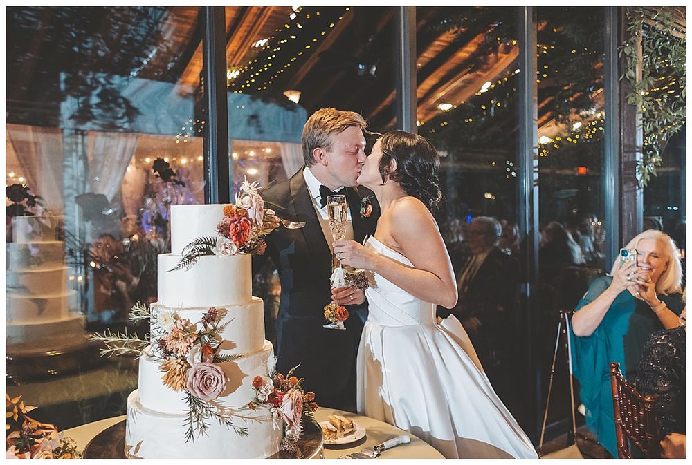 Wedding reception guests dance and celebrate under warm lighting in an elegant indoor venue.