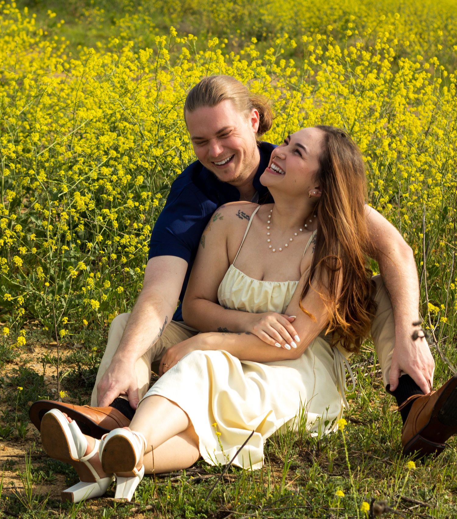 A couple relaxes together in a vibrant field of yellow wildflowers on a sunny spring day.