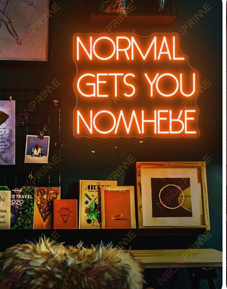 A series of orange neon signs mounted on a dark wall displaying phrases like "NORMAL" and "GETS YOU NOWHERE".