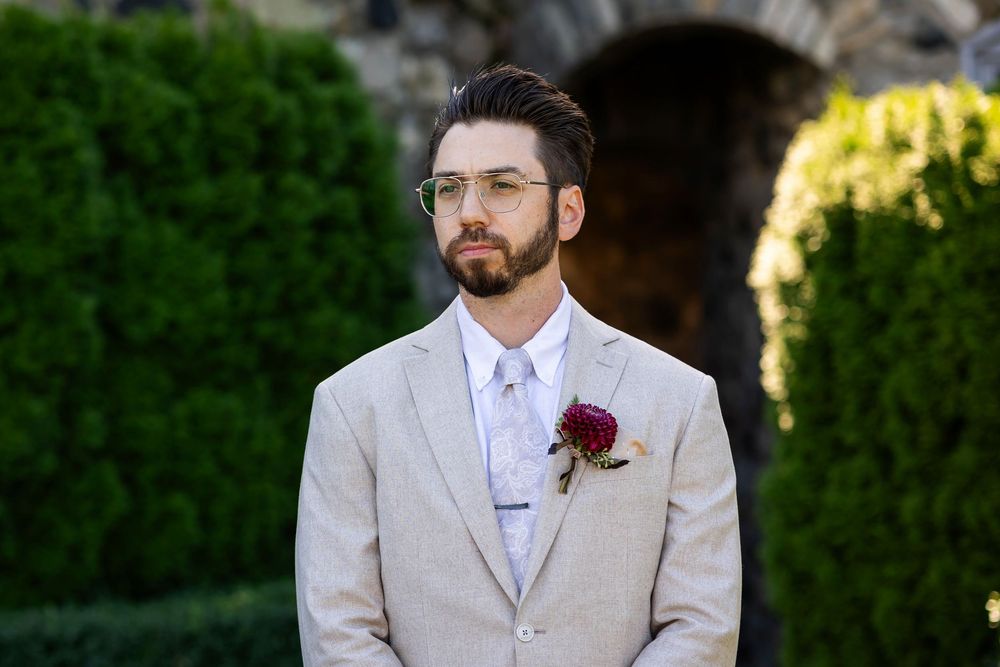 The groom outside in the butterfly garden waiting for his bride for the first look in a summer Michigan wedding