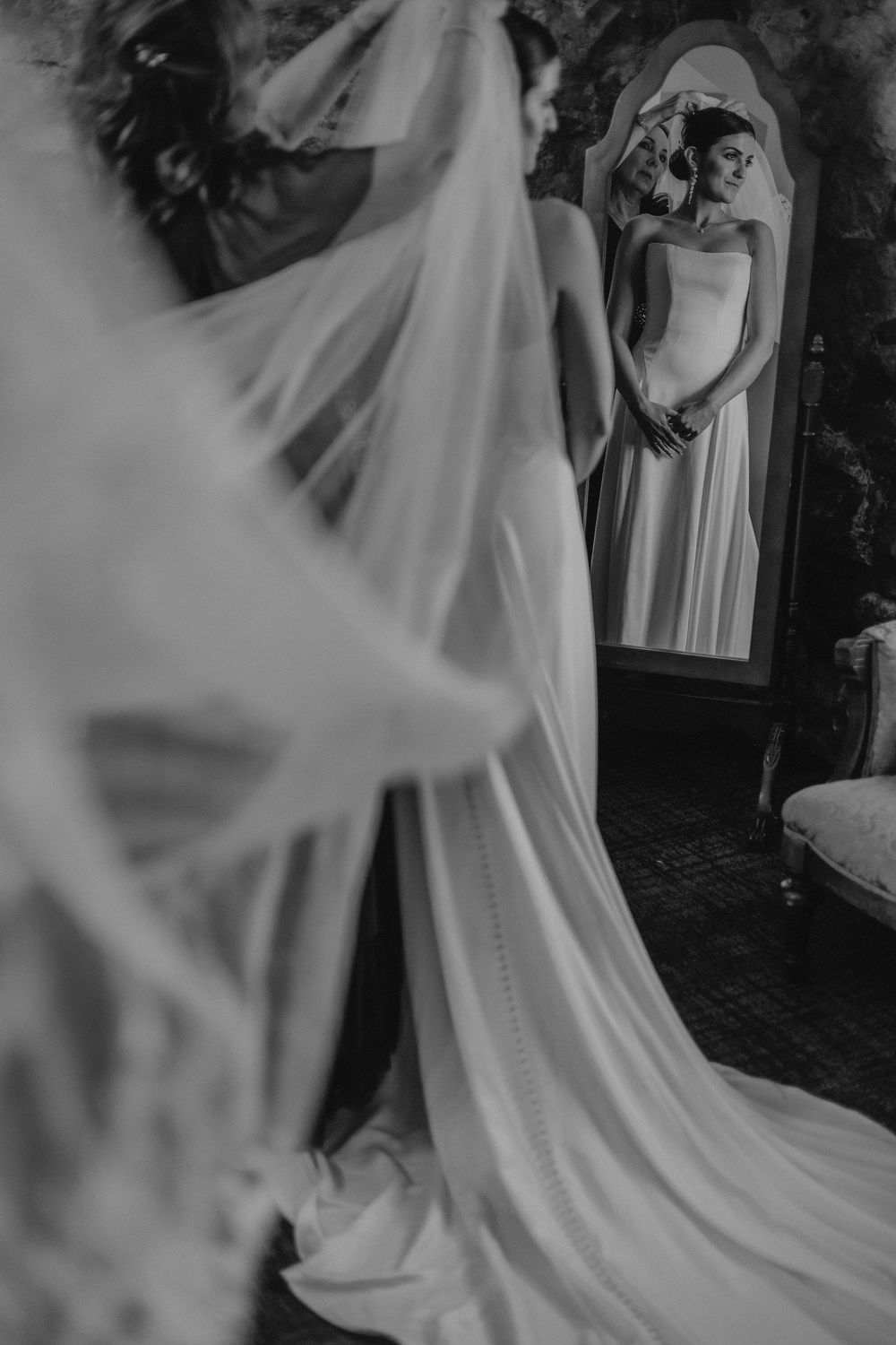 A flowing white wedding dress train and veil captured in black and white photography