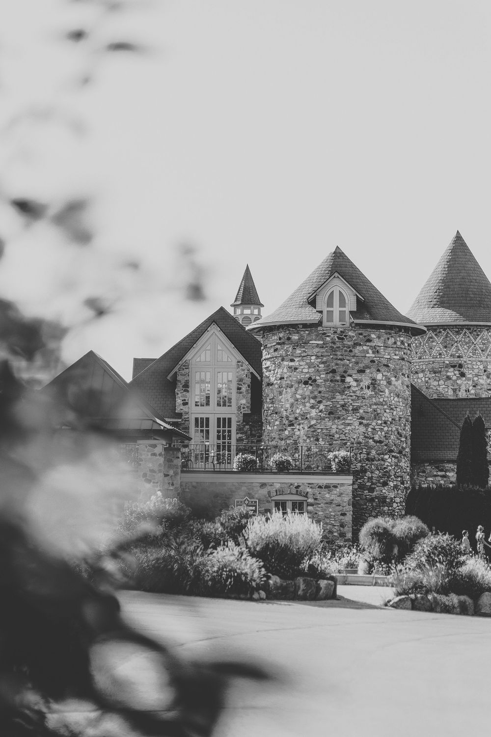 A black and white panoramic view of a stone castle-like building with Gothic architectural features and landscaped grounds.