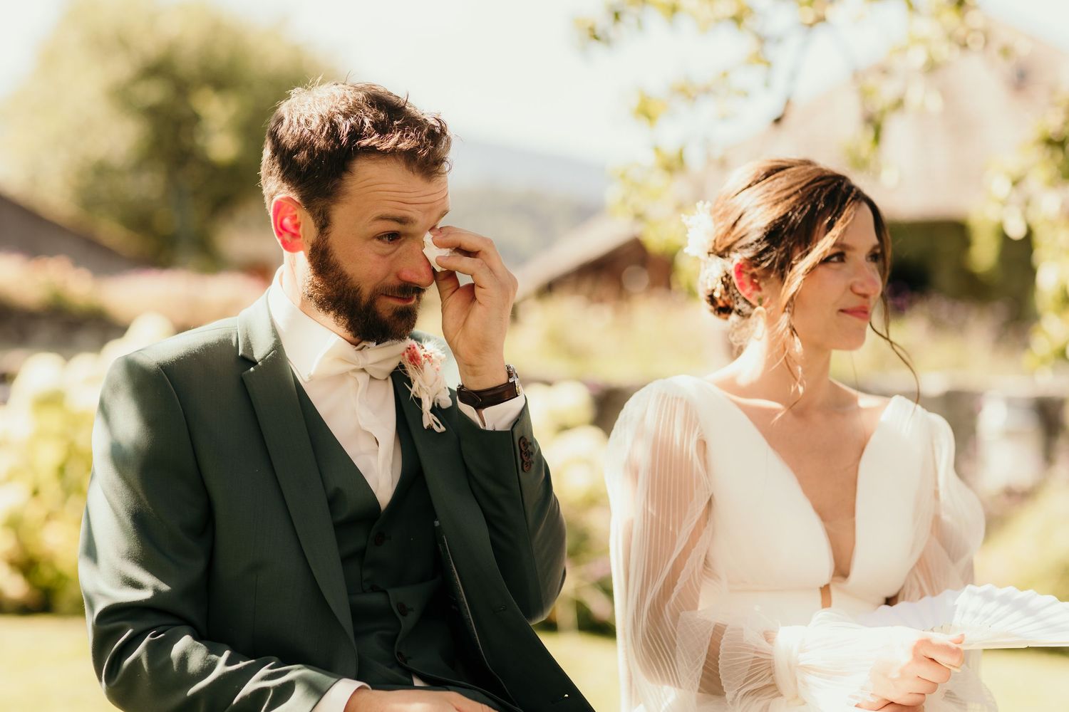Couple shares emotional moment during outdoor wedding ceremony on sunny day.