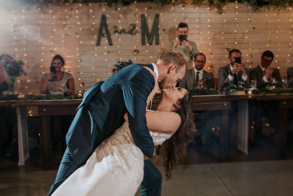 Wedding reception venue decorated with string lights, white brick walls and rustic accents.