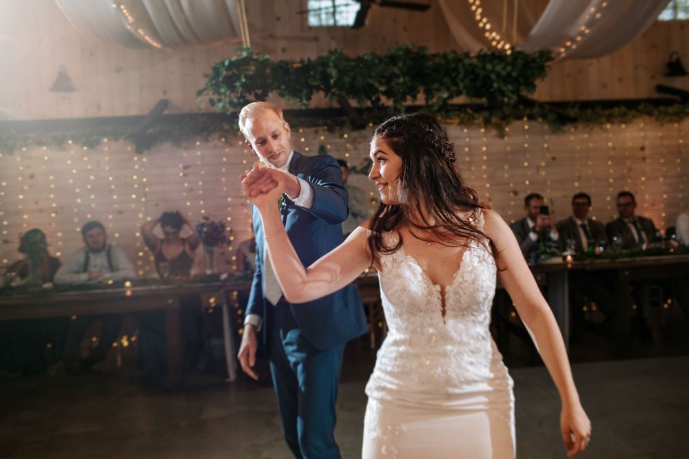 Dynamic dance moves captured during wedding reception in rustic venue.
