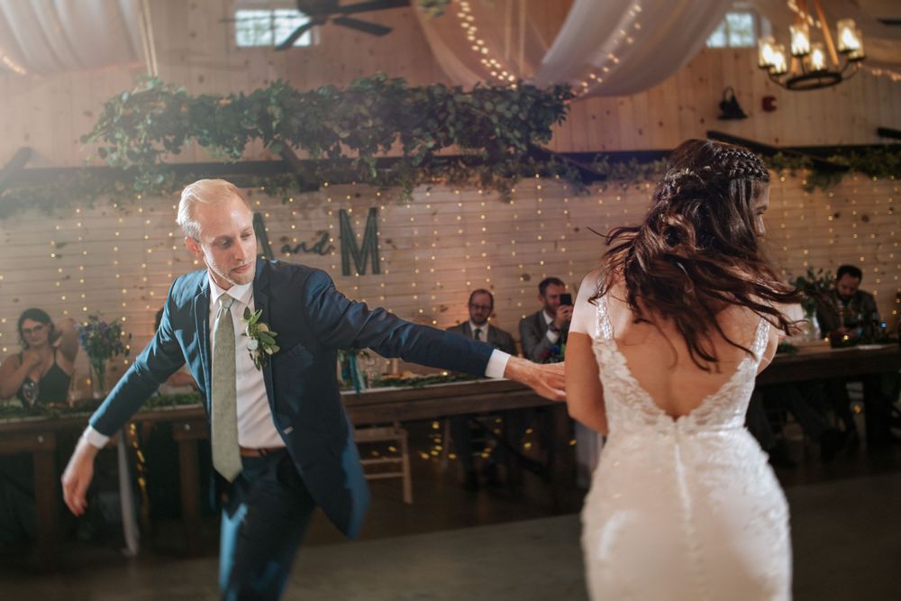 Joyful dance moves captured during wedding reception with string lights and greenery.