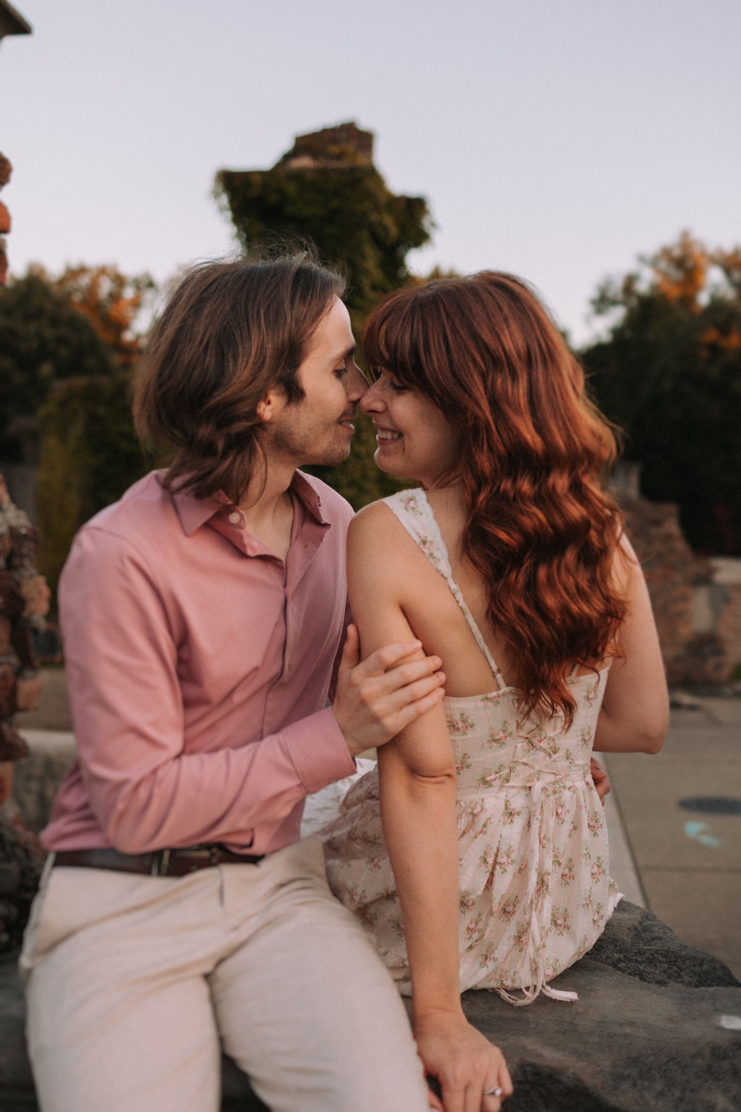 An intimate moment captured between a couple on stone ruins at dusk.