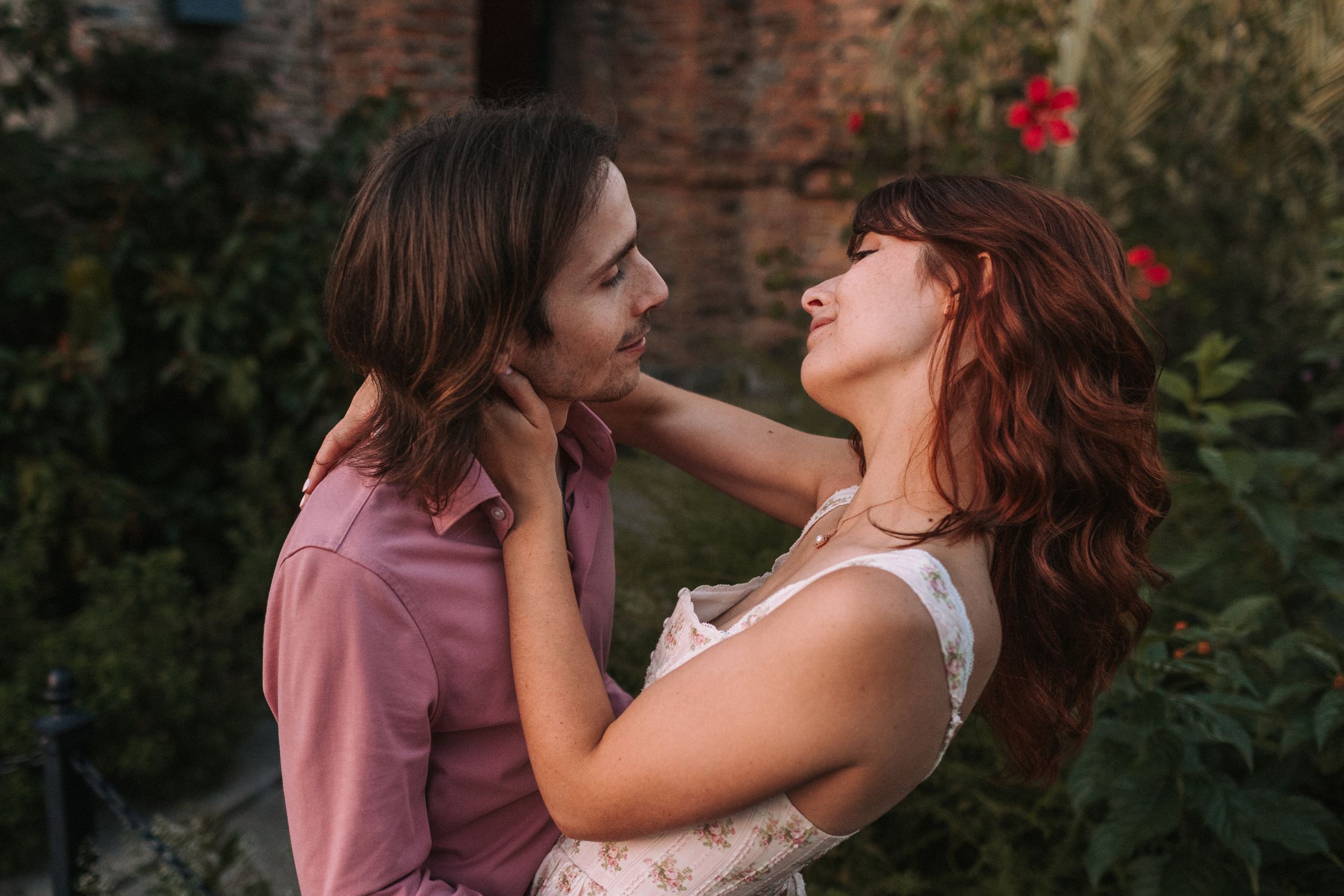 Intimate couple embracing near brick ruins during golden hour photography session.