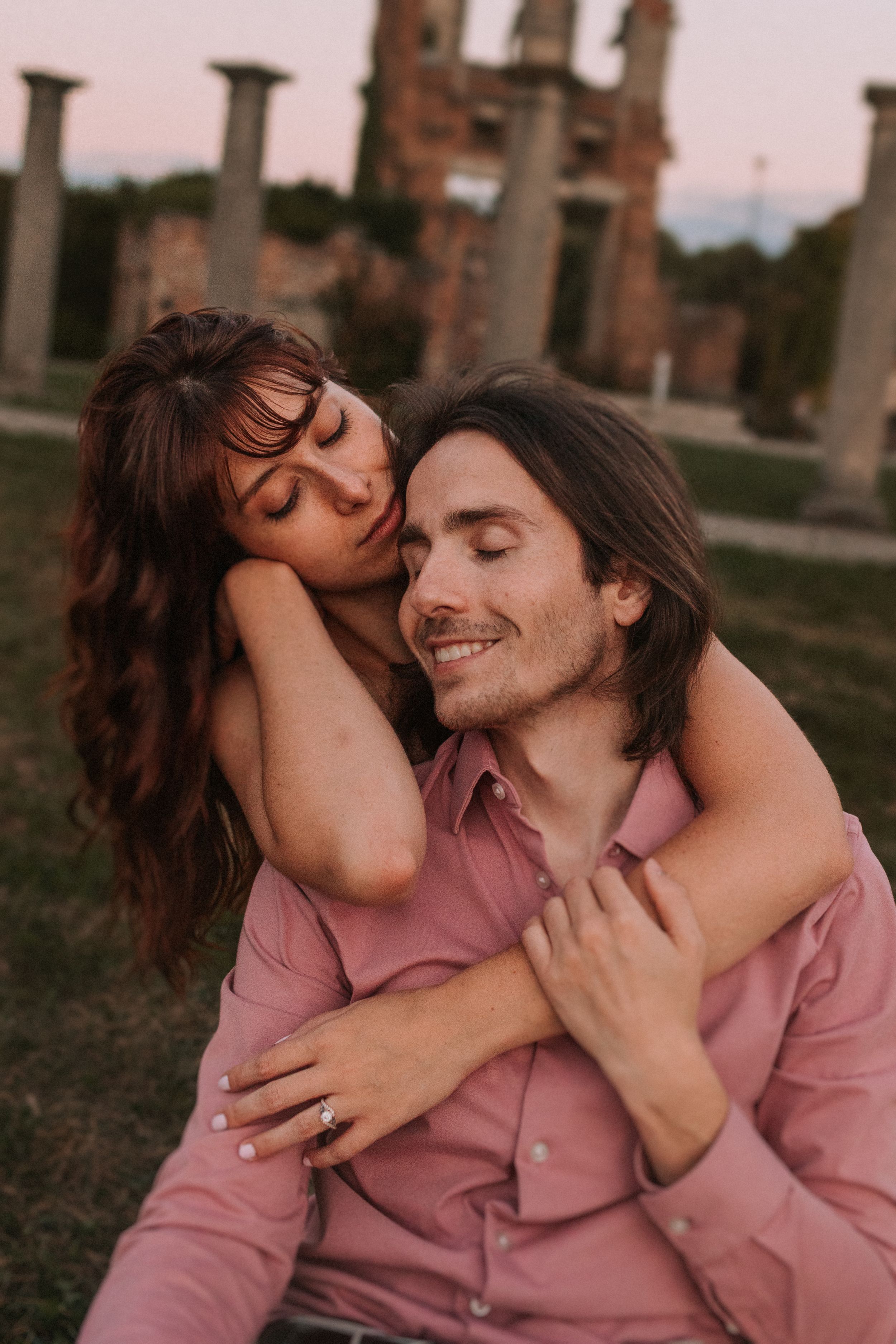 Couple sharing affectionate moments during outdoor photoshoot near brick ruins.