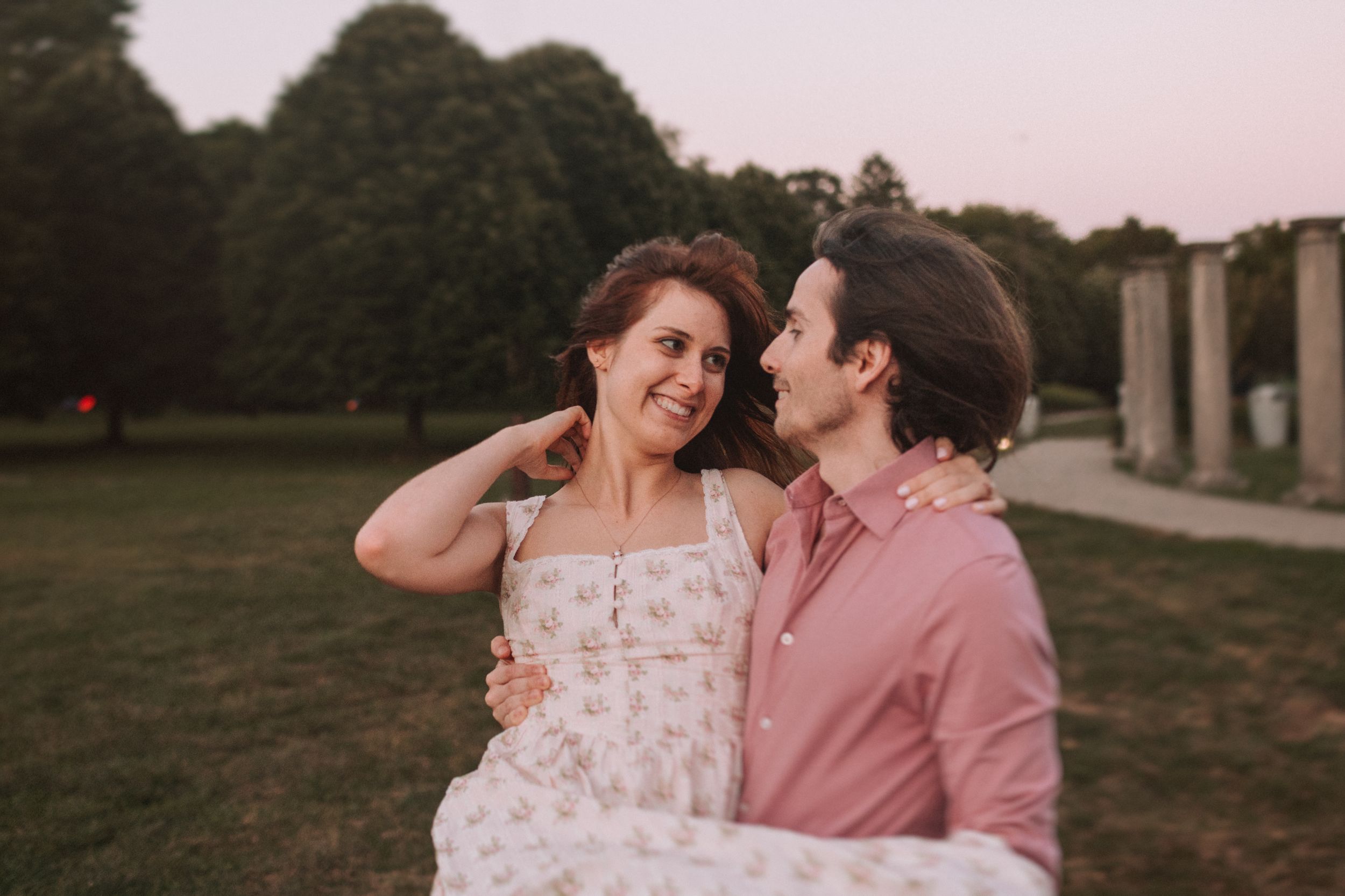 Couple laughing together during romantic sunset photo session near historic columns.