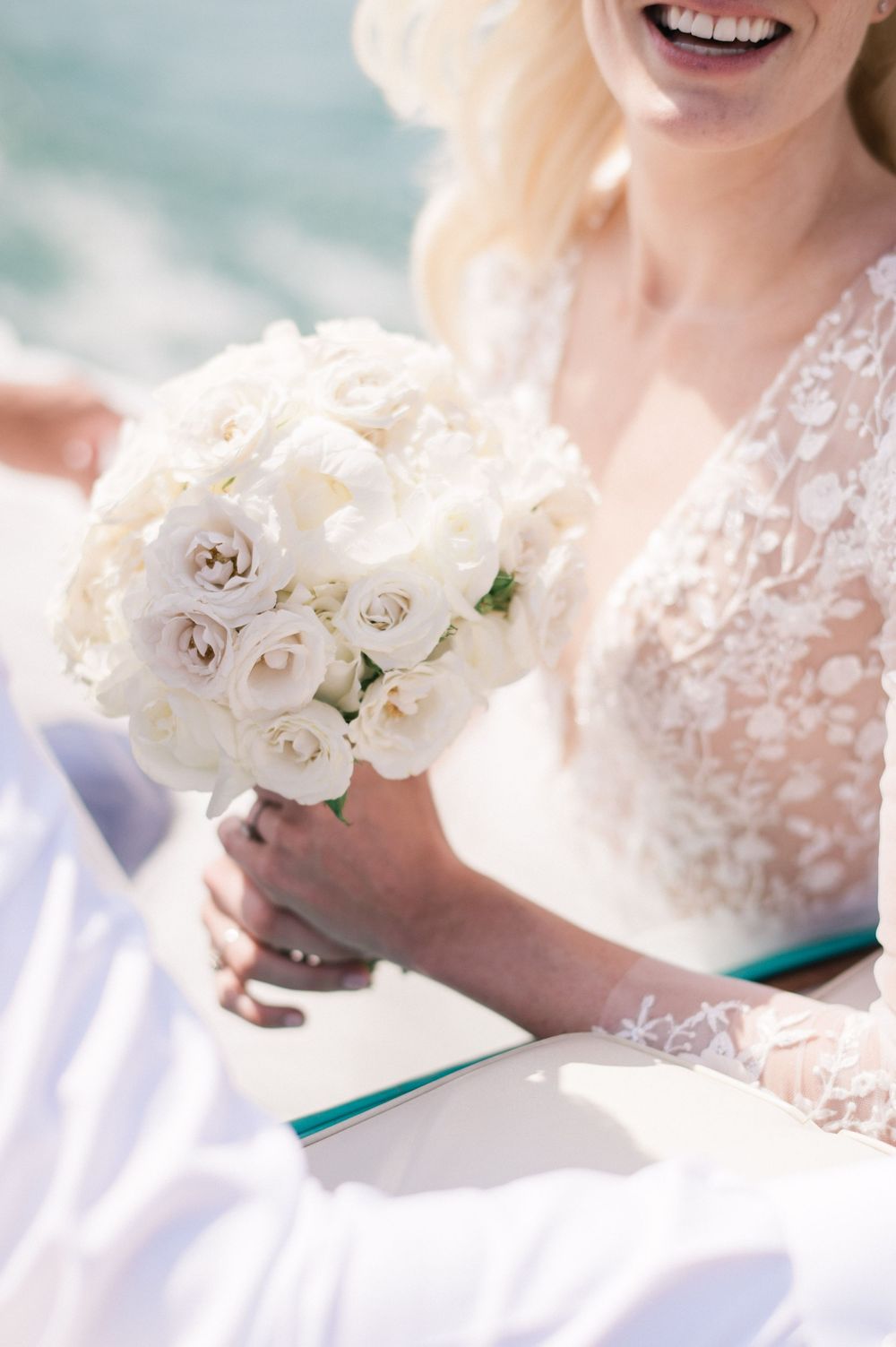 Bride showing her bouquet during the boat trip on her Riva boat
