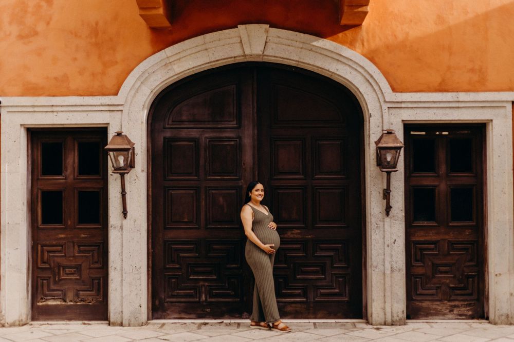 A long row of wooden doors with ornate panels and white trim line a terracotta-colored wall in a historic building.