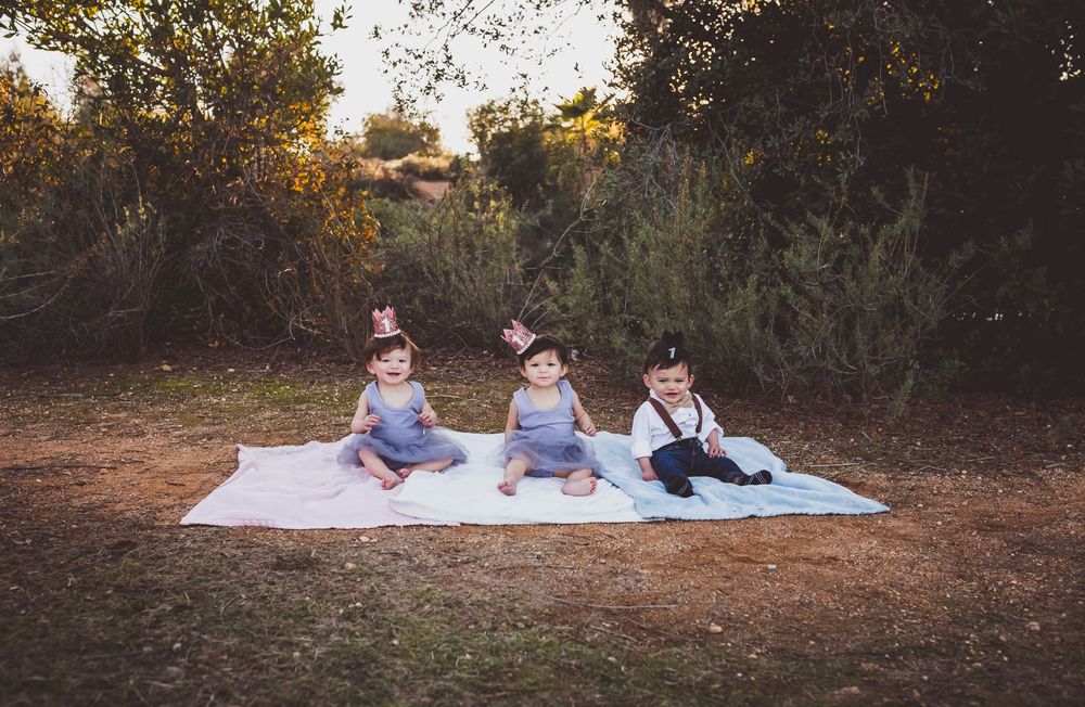 People sitting on a white blanket in a grassy field at sunset creating a panoramic scene.