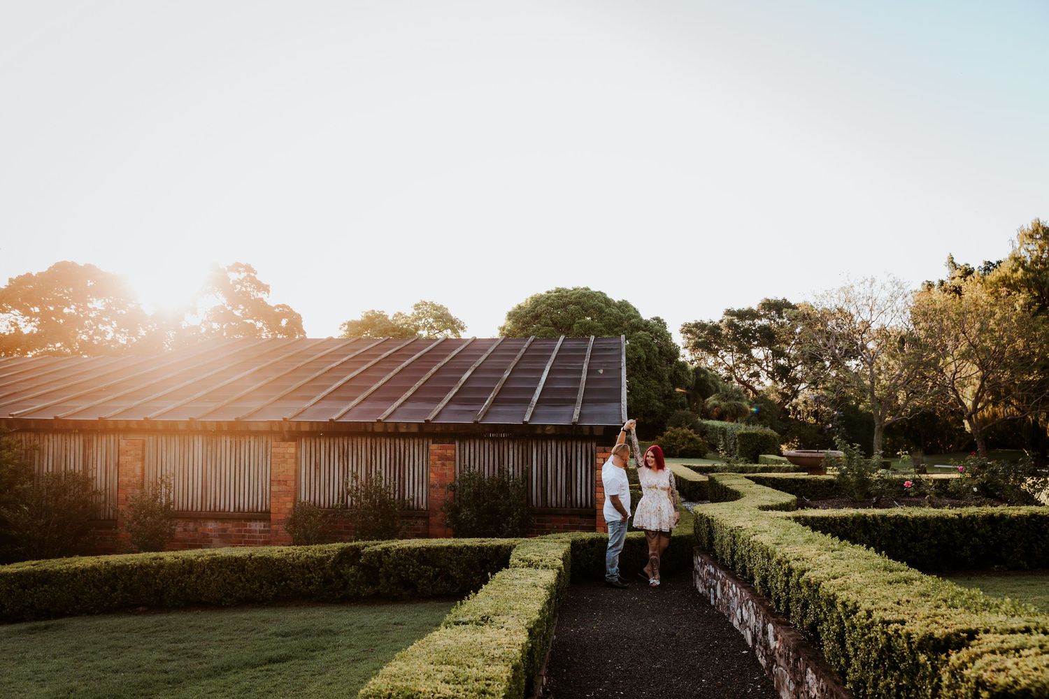 Golden sunset over rustic barn venue with solar panels visible on roof.