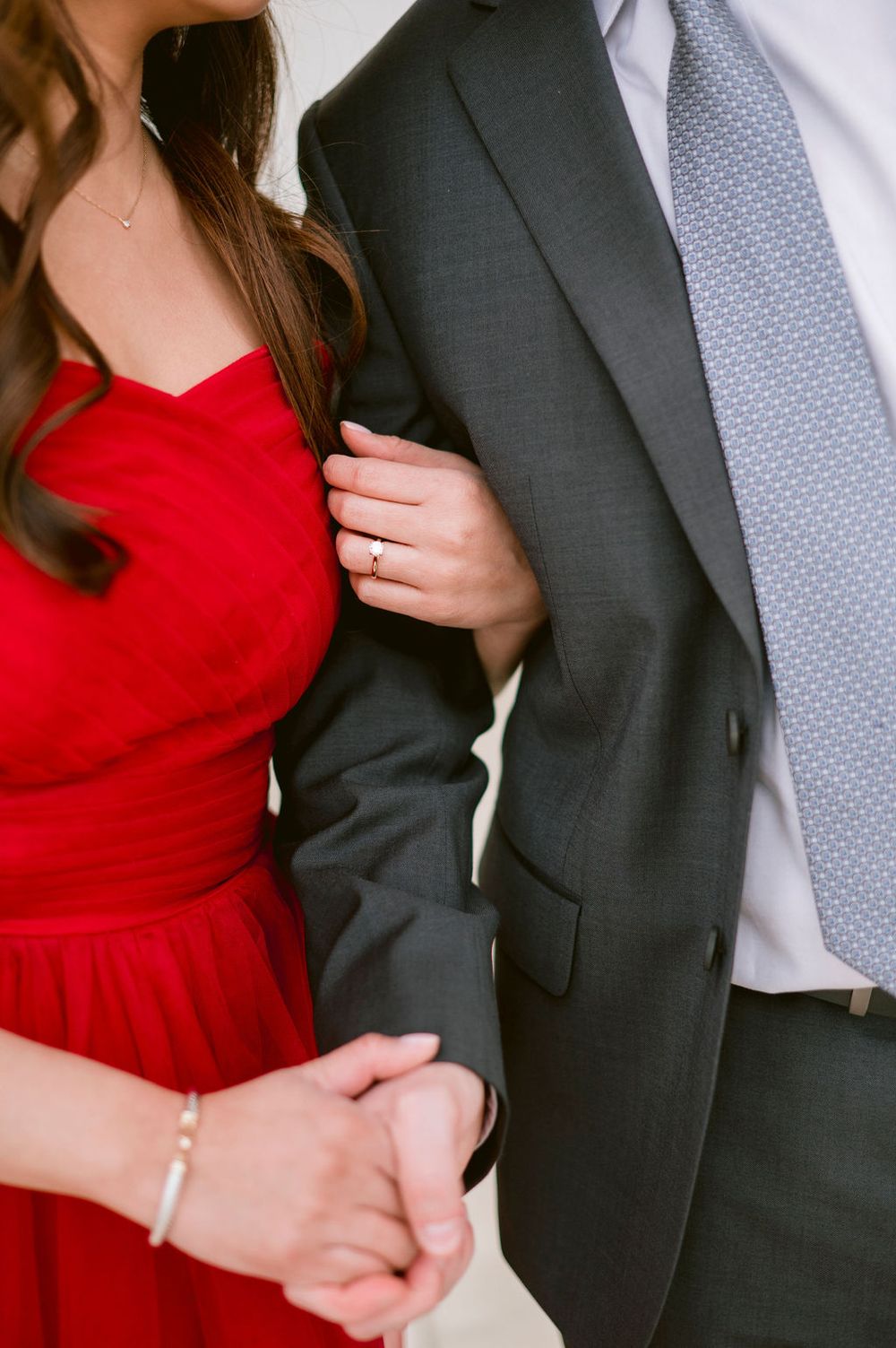 Close-up shots of a couple in formal attire with red dress and dark suit embracing in front of white columns.